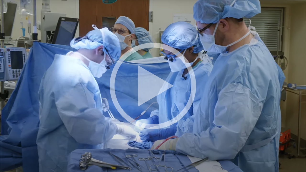 Video play button and an image of Dinee C. Simpson, MD, and her team performing surgery. 