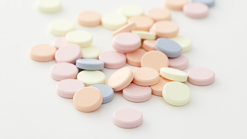 An assortment of colored antacid tablets on a light grey table. 