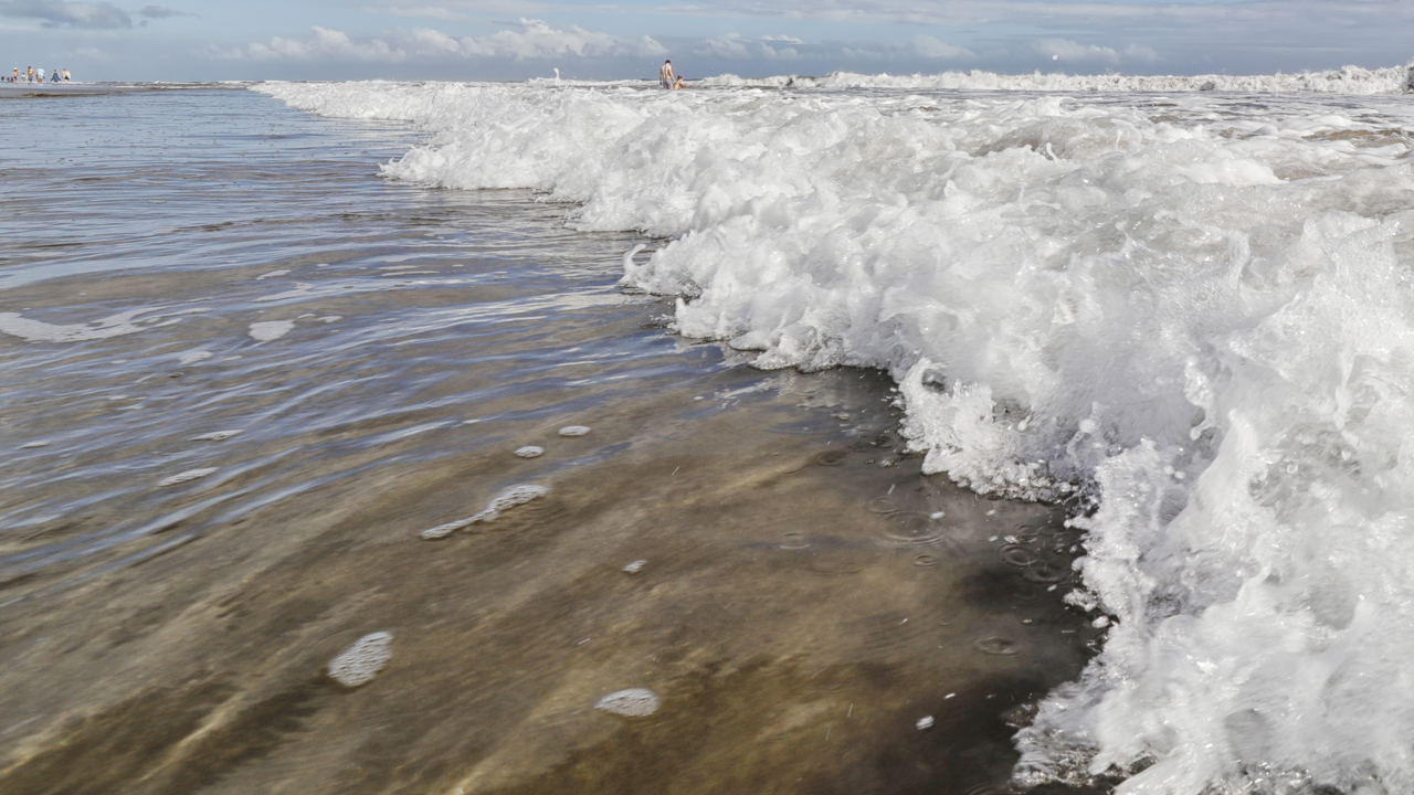 Waves crashing on a beach on a sunny day.