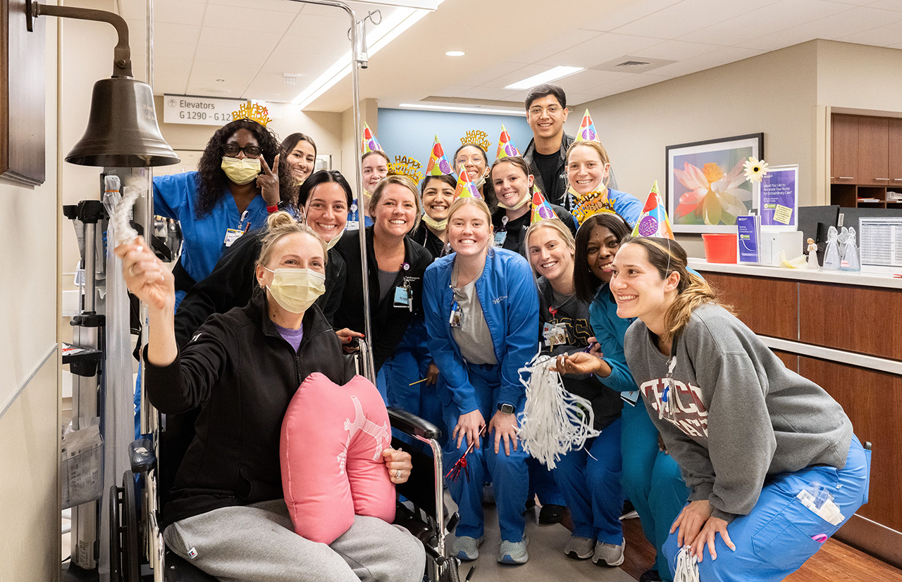  Mandy Wilk ringing a bell surrounded by her care team.