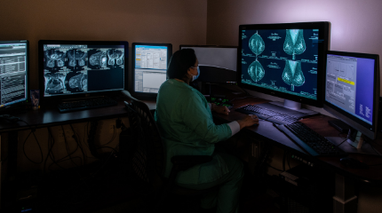 A northwestern medicine physician examining breast imaging on several computer screens.