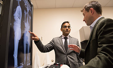 Northwestern Medicine Spine Surgeons Dr. Tyler Koski and Alpesh Patel reviewing a patient's spine scans.
