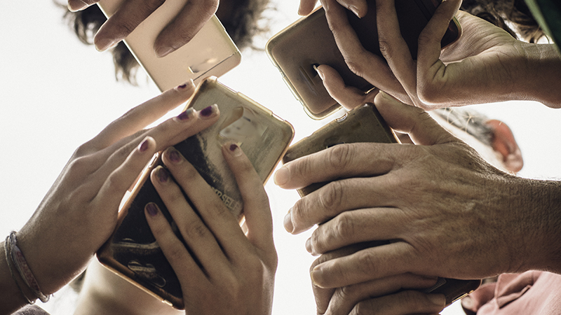 Low angle view of people grouped together using their smart phones. 