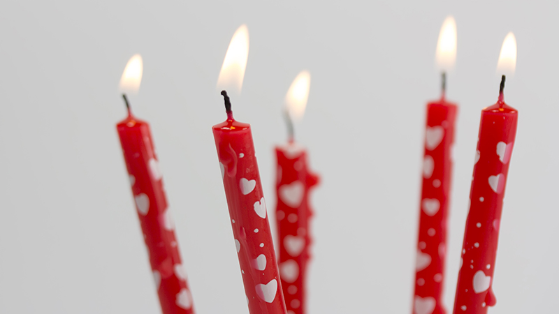 Lit red birthday candles with white hearts.