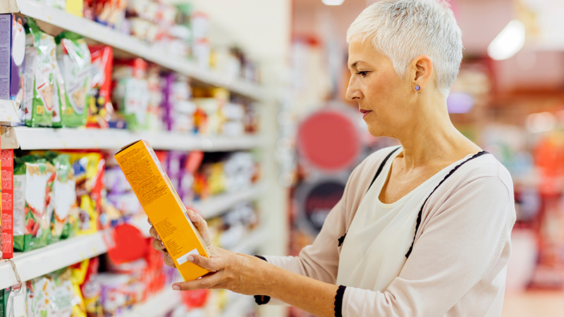 A person reviewing the front of a cereal box while grocery shopping. 