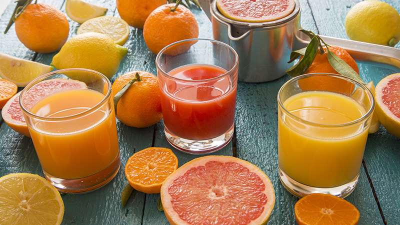 Glasses of orange and grapefruit juice on a blue wooden table. 