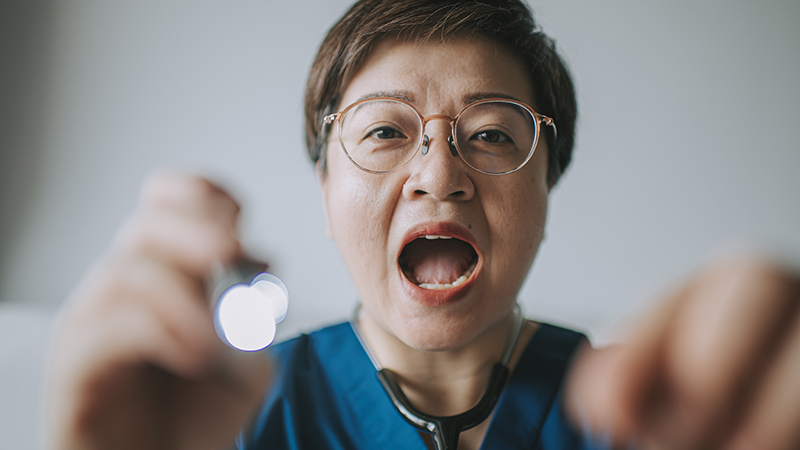 A physician about to look into a patient’s mouth.