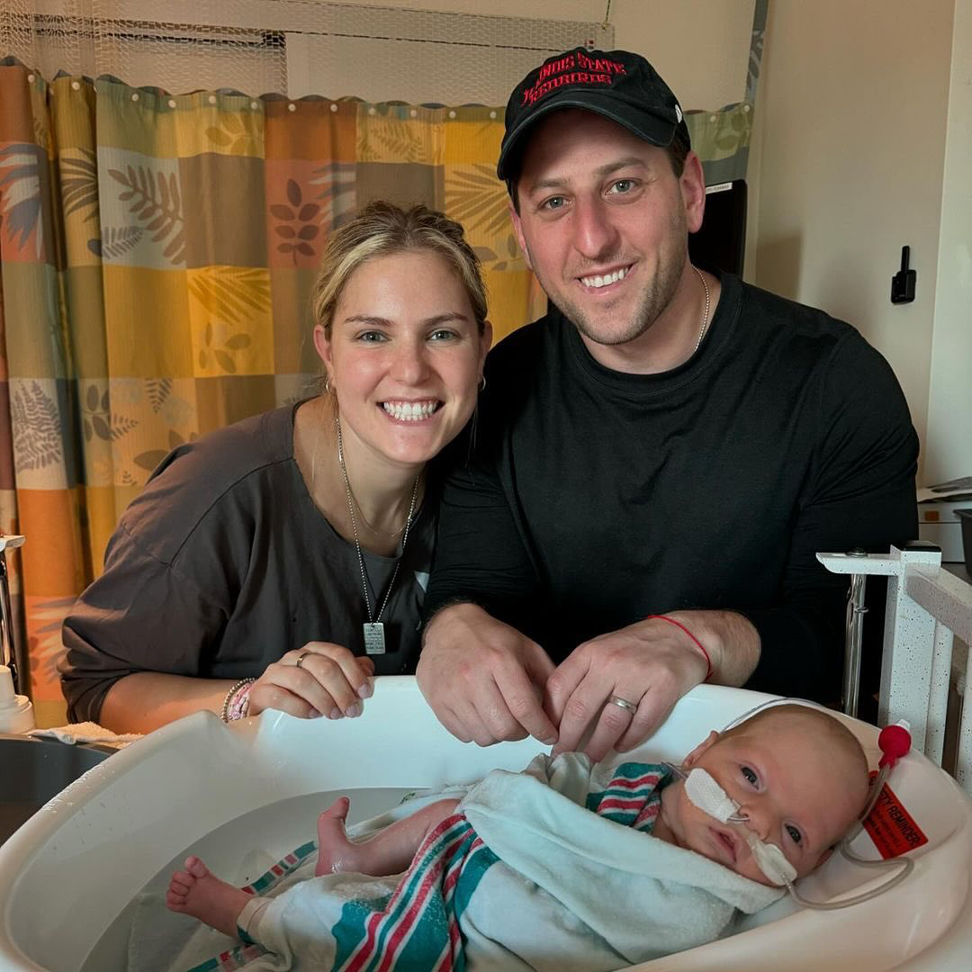 Parents smiling and posing with their baby